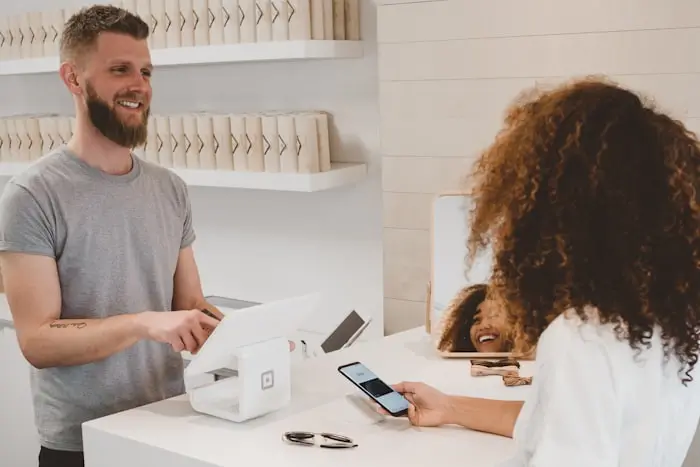Klientė atlieka bekontaktinį mokėjimą telefonu prie kasos aparato parduotuvėje