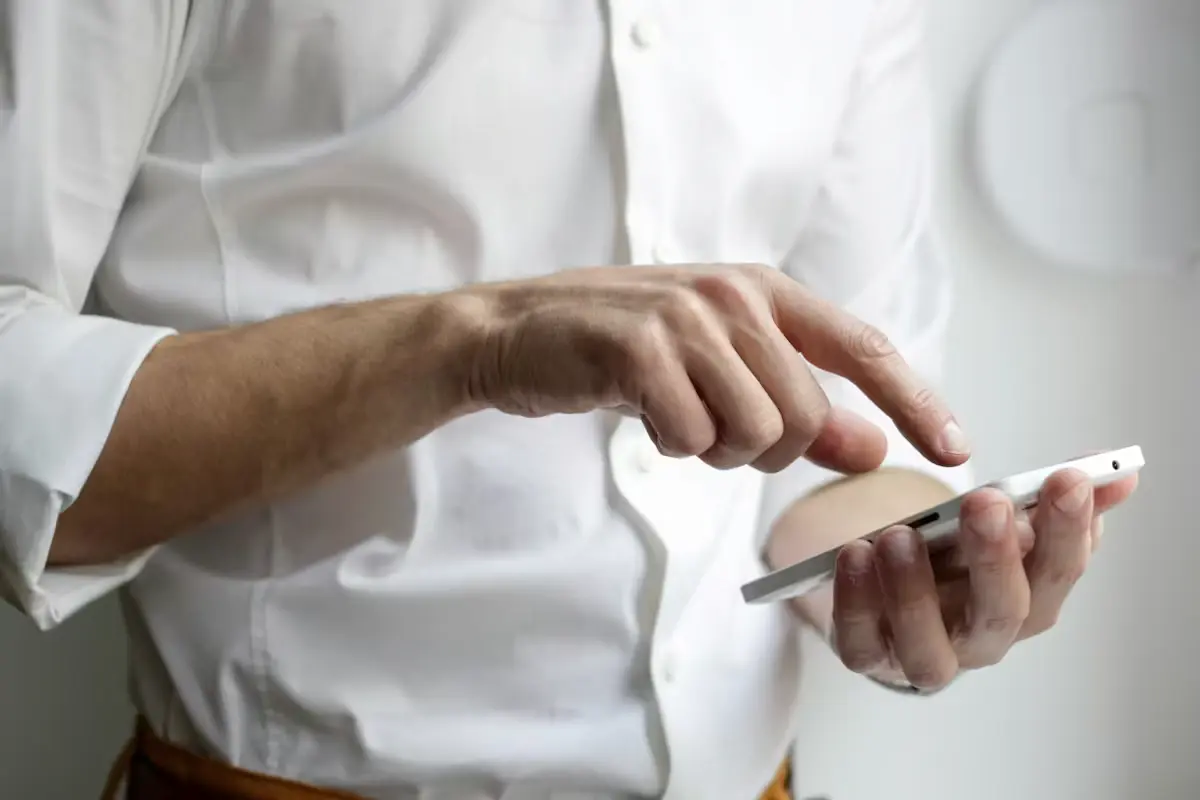 A man in a white shirt tapping the screen of a smartphone