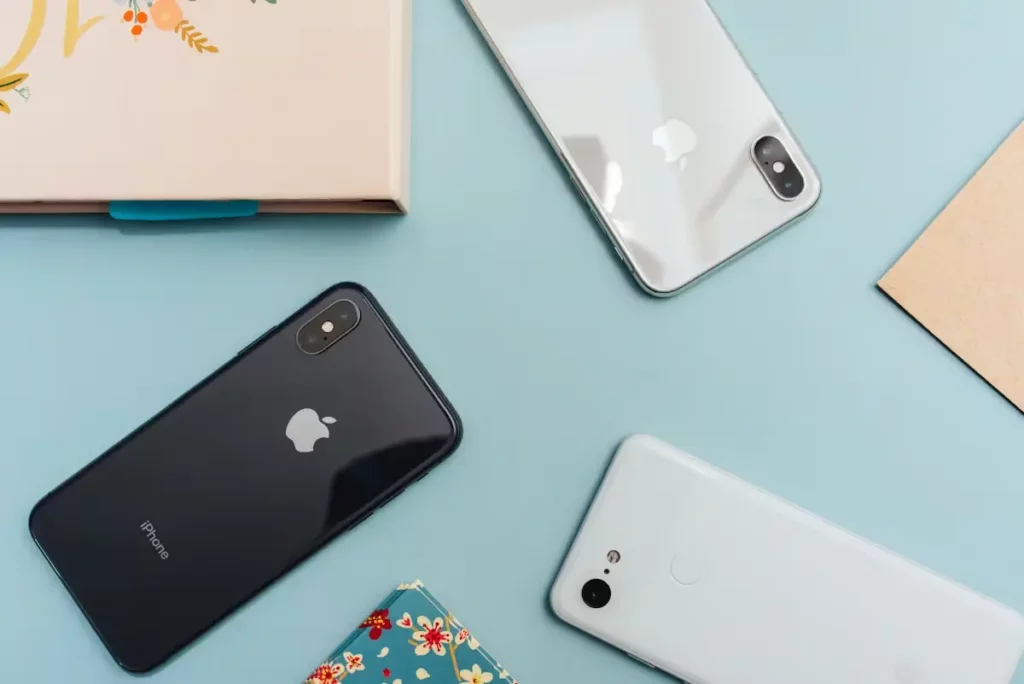 Three smartphones laid out on a light blue background next to a notebook