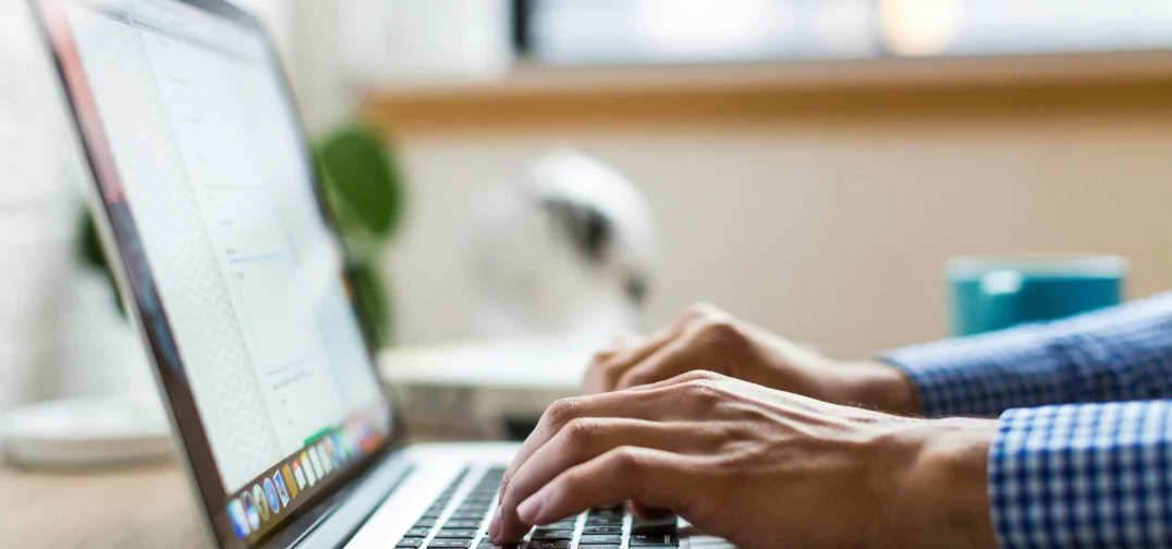 Žmogus rašo nešiojamuoju kompiuteriu, ekrane atidaryta internetinė forma