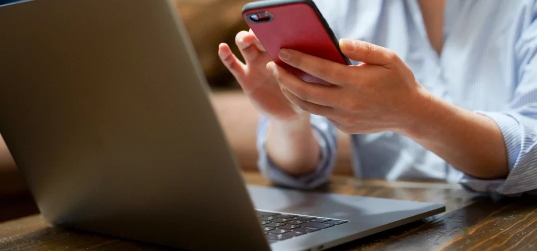 Woman sending an SMS marketing message while sitting at a laptop